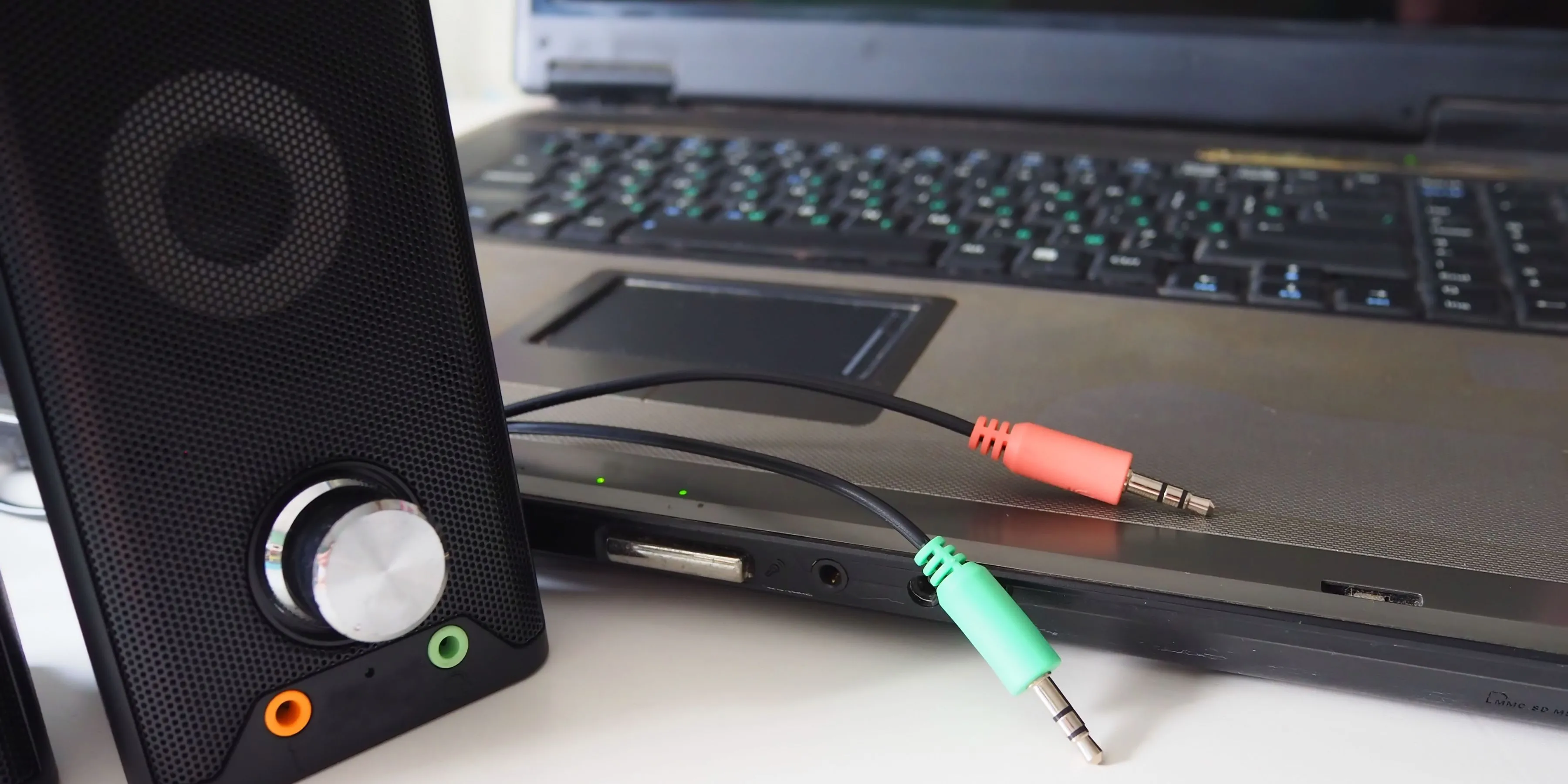 Loa và các loại cáp âm thanh 3.5mm nằm cạnh PC, minh họa sự phức tạp của việc quản lý dây cáp khi chơi game
